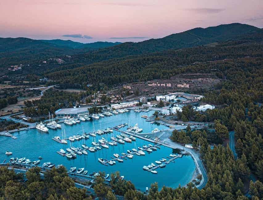 aerial shot of boats in a marina with blue water and pink sky