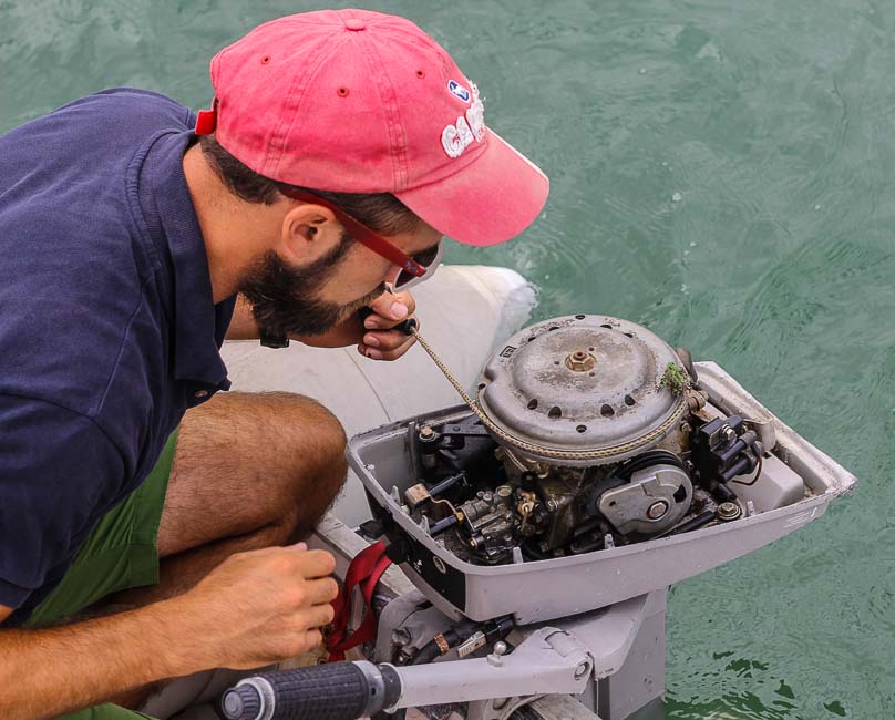 man in red hat inspecting an outboard motor
