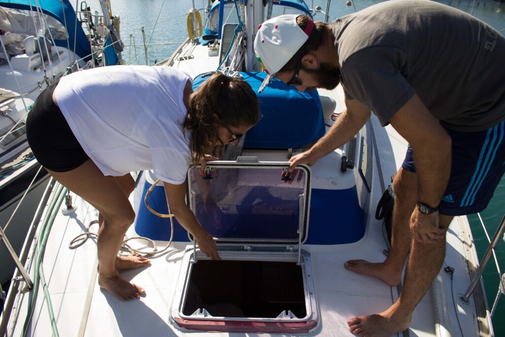 woman and man inspect a leaking hatch on a sailboat