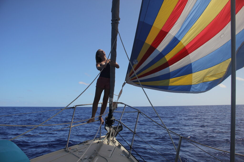 Woman standing on a boat at bow next to asymmetrical spinnaker