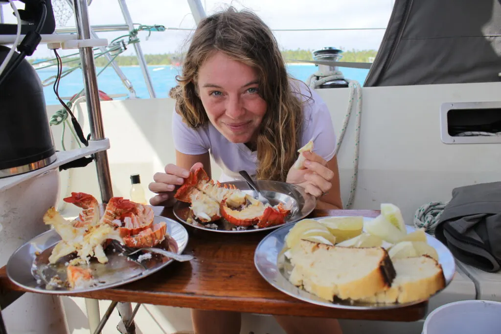 Woman smiling and eating lobster in cockpit of sailboat