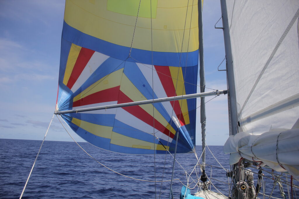 poled out asymmetrical spinnaker and triple reefed mainsail