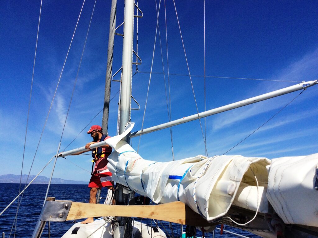 Man holding pole on foredeck of sailboat