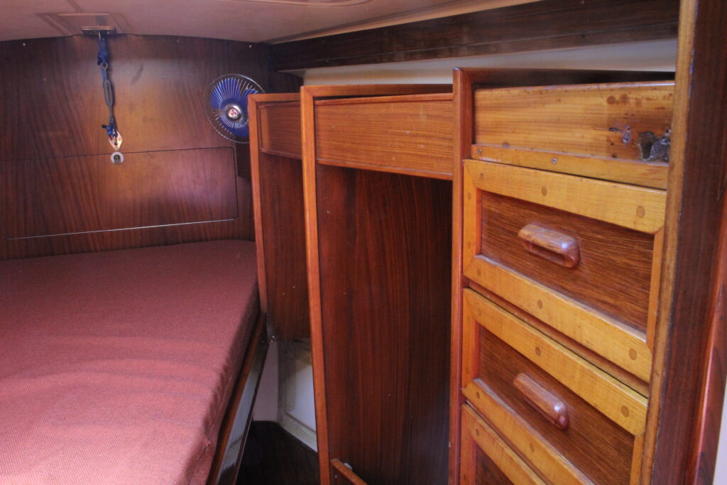 Sailboat berth with red mattress and wooden drawers