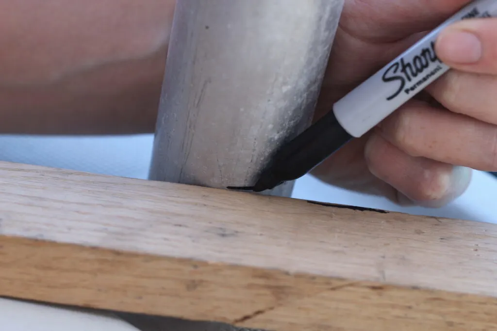 scribing a line onto an aluminum tube using a permanent marker and wooden block